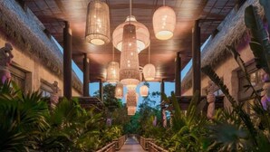 A wooden pathway flanked by lush tropical plants leading to a thatched-roof building with hanging lanterns. - 2BD Grand Bliss Vidanta Resort RM (Playa del Carmen)