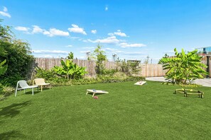 Un jardin avec une pelouse artificielle, une clôture en bois et un panier de basket.
