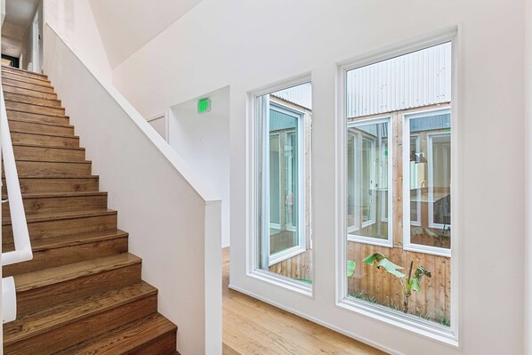 A wooden staircase leading to a room with large windows and a visible exit sign.