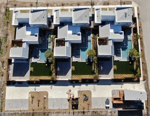 Un hotel moderno de varios pisos con piscina en la azotea, balcones privados y estacionamiento.