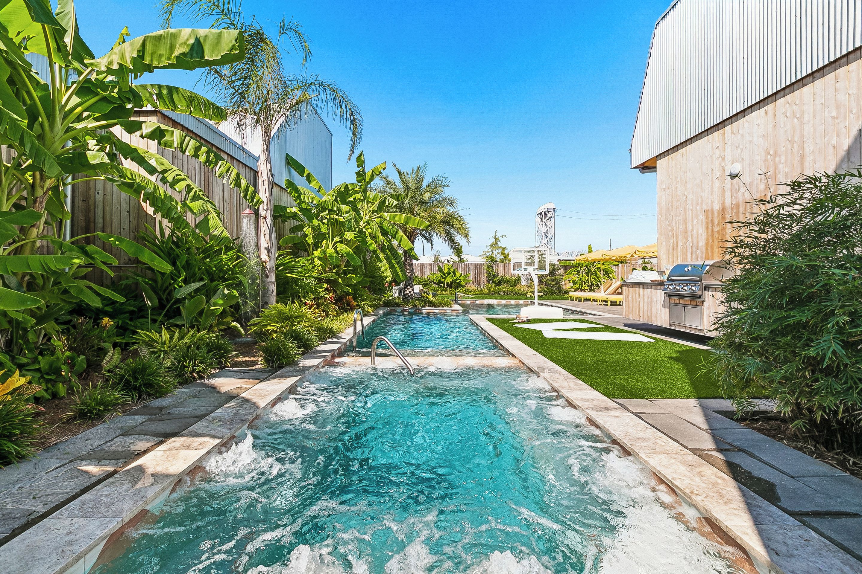 A swimming pool with a wooden deck and a grassy area.