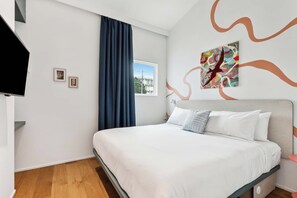 Une chambre à coucher moderne avec un lit, une fenêtre et un tableau accroché au mur.