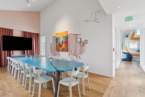 Een vergaderruimte met een lange tafel, witte stoelen, een grote flatscreen-tv en kunstwerken aan de muur.