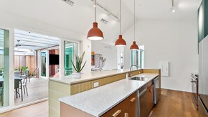 Una cocina moderna con una isla grande, electrodomésticos de acero inoxidable e iluminación colgante.