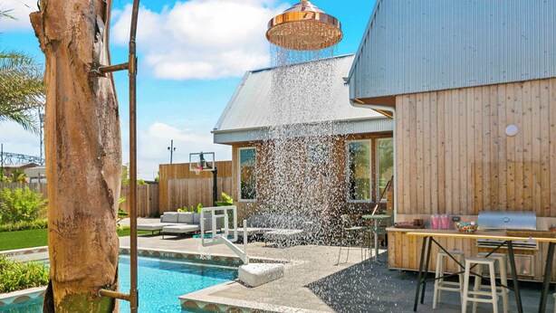 Un patio trasero con piscina, terraza de madera y zona de barbacoa.