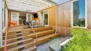 Una terraza de madera con una escalera que lleva a un porche cubierto.