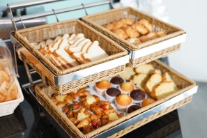 Ein reichhaltiges Buffet mit verschiedenen Backwaren, darunter Brot, Gebäck und Muffins.