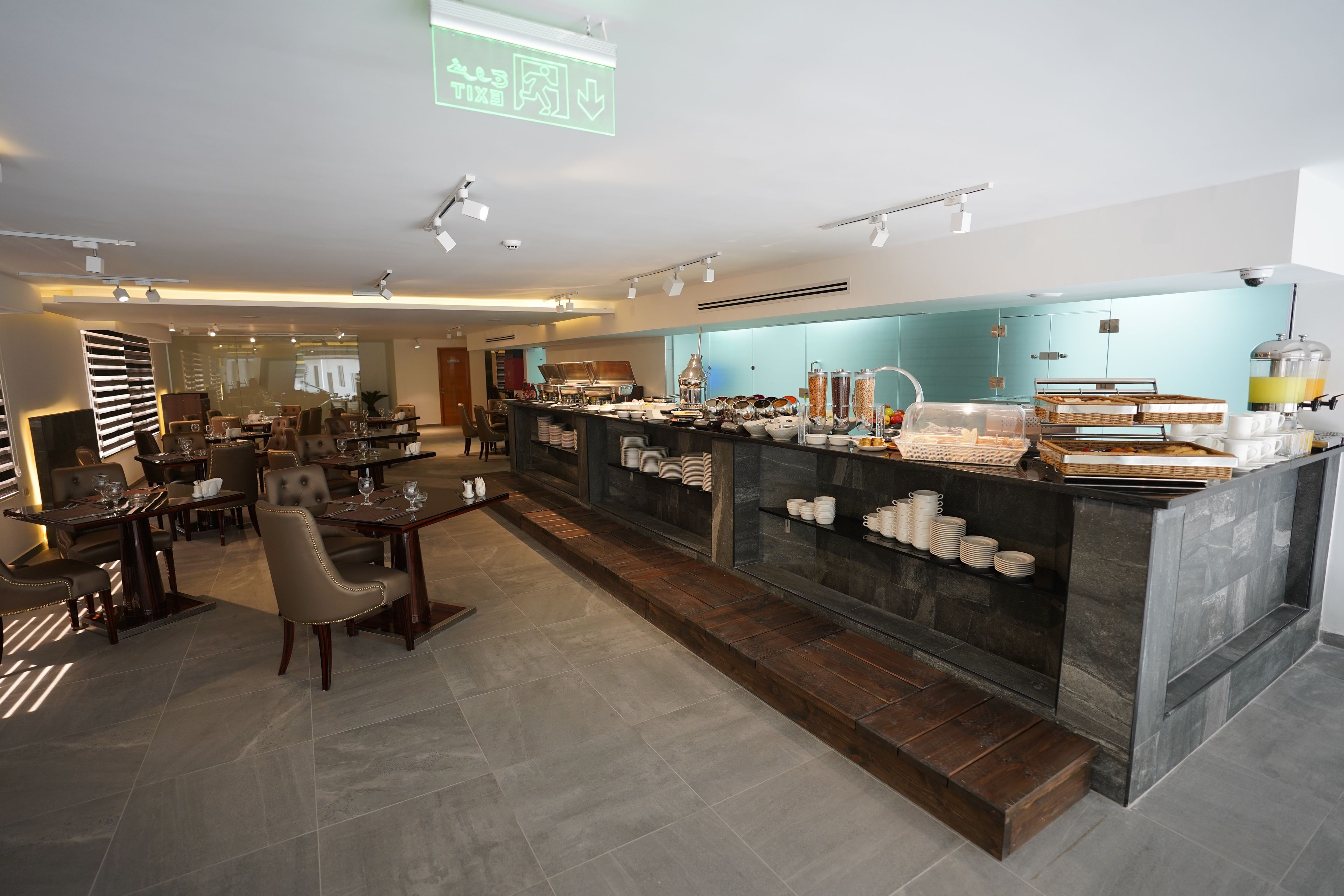 A modern restaurant with a central bar area, seating arrangements, and a buffet setup.