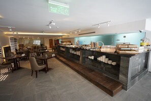 A modern restaurant with a central bar area, seating arrangements, and a buffet setup. - Gloria Boutique Hotel (Amman)