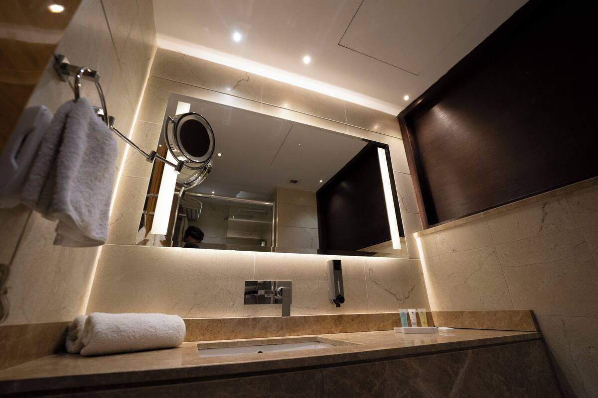 A modern bathroom with a large mirror, a sink, and a towel rack.