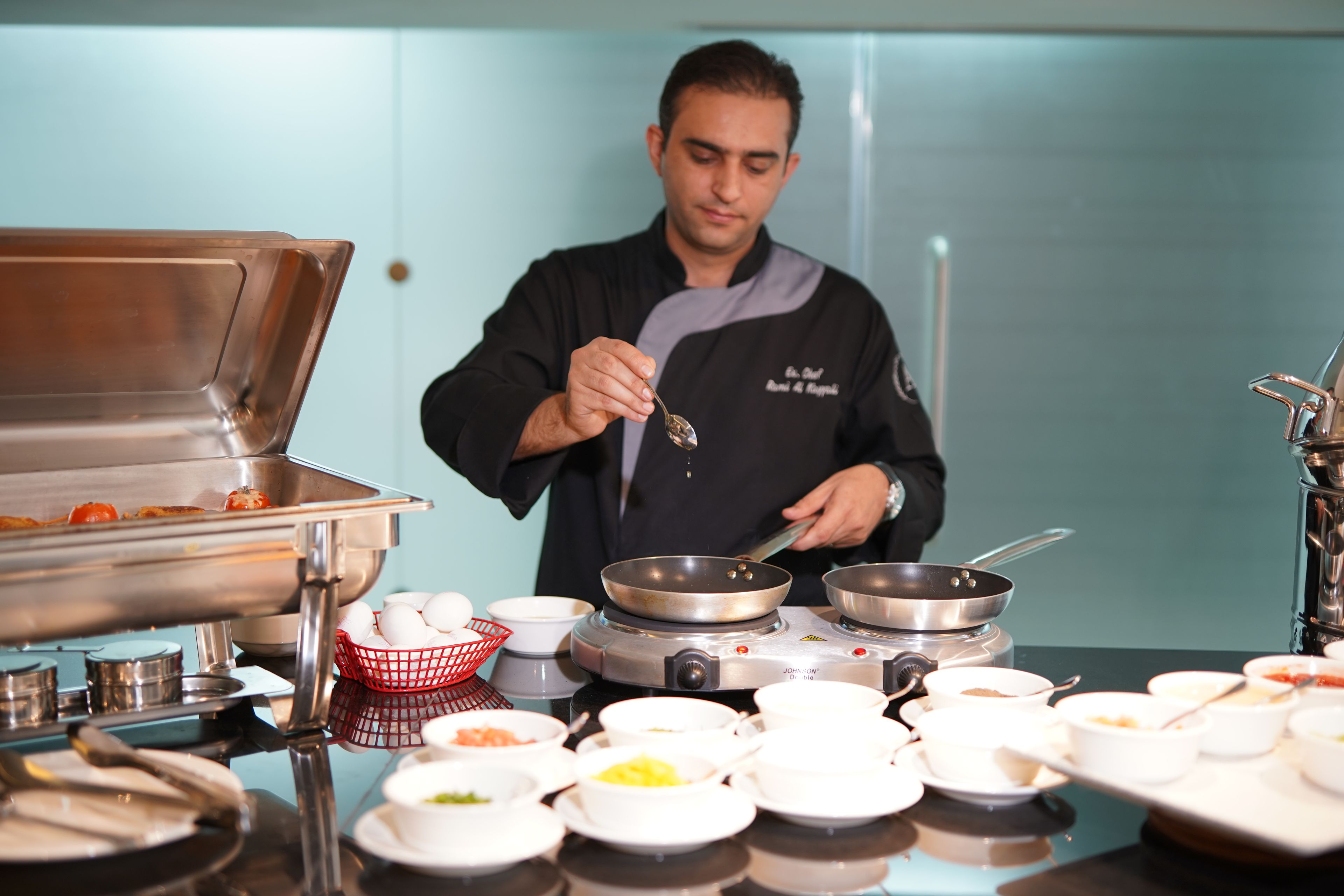 Een kok bereidt eten in een professionele keuken, met diverse kookgerei en ingrediënten.