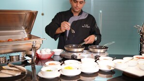 A chef preparing food in a professional kitchen with various cooking utensils and ingredients. - Gloria Boutique Hotel (Amman)