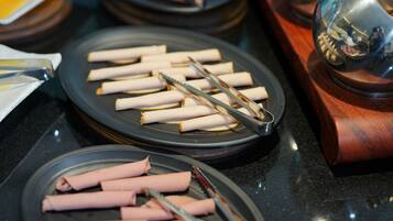 Un buffet avec plusieurs plateaux de viandes tranchées et des pinces pour se servir.