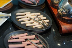 A buffet setup with multiple plates of sliced meats and tongs. - Gloria Boutique Hotel (Amman)