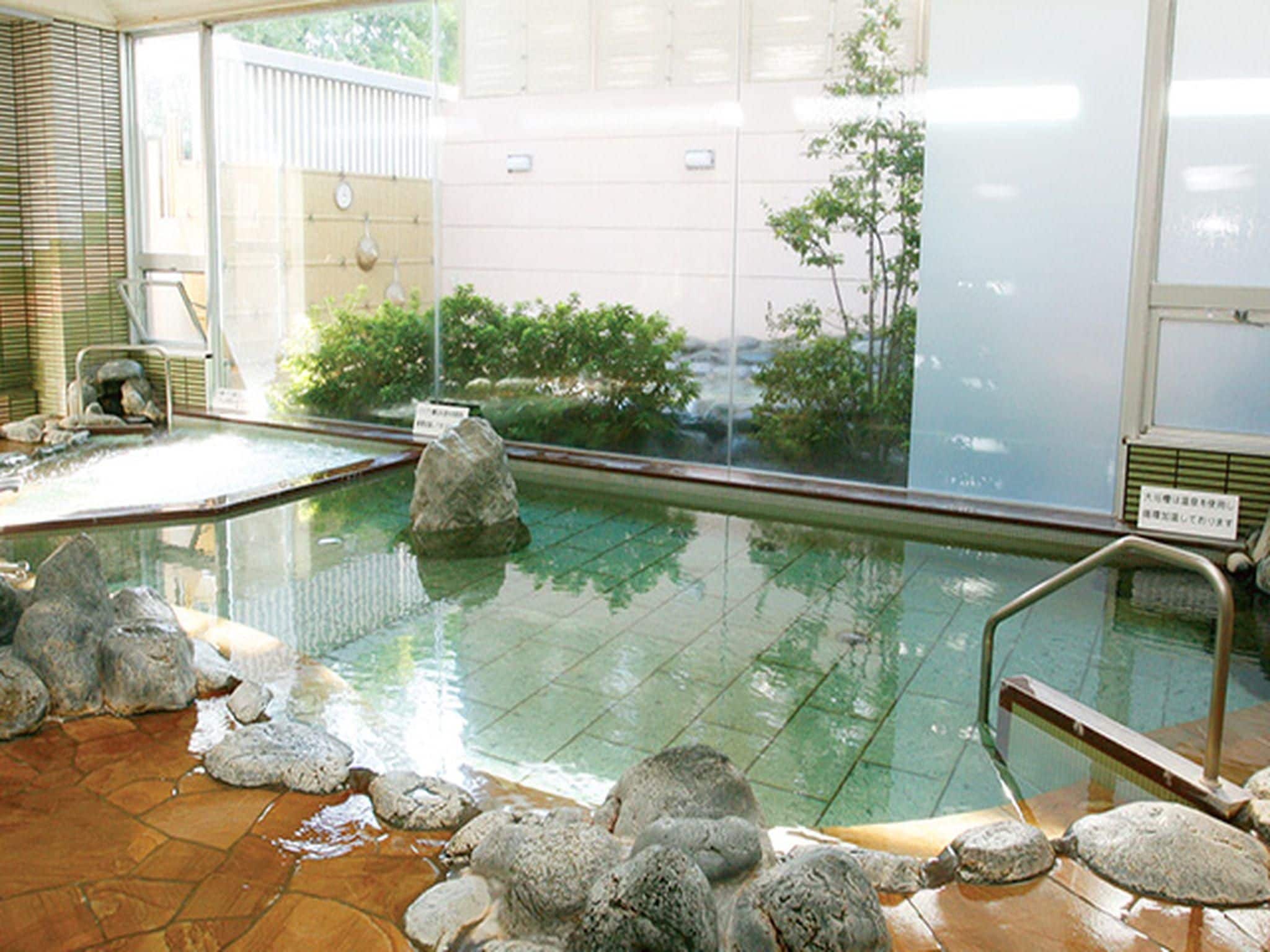 An indoor swimming pool with clear water, surrounded by rocks and tiles.