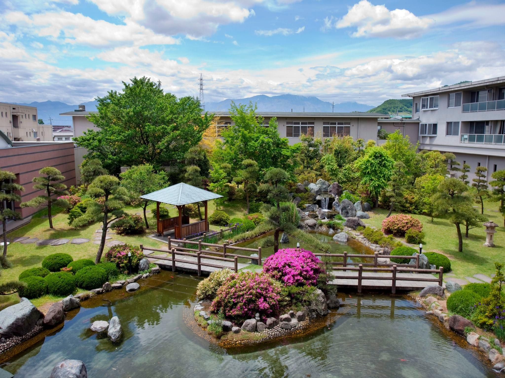 Un jardín japonés tradicional con un estanque de carpas koi, un puente de madera y un pabellón.