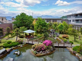 Um jardim japonês tradicional com um lago de carpas koi, uma ponte de madeira e um gazebo.