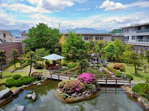 Ein traditioneller japanischer Garten mit einem Koiteich, einer Holzbrücke und einem Gazebo.