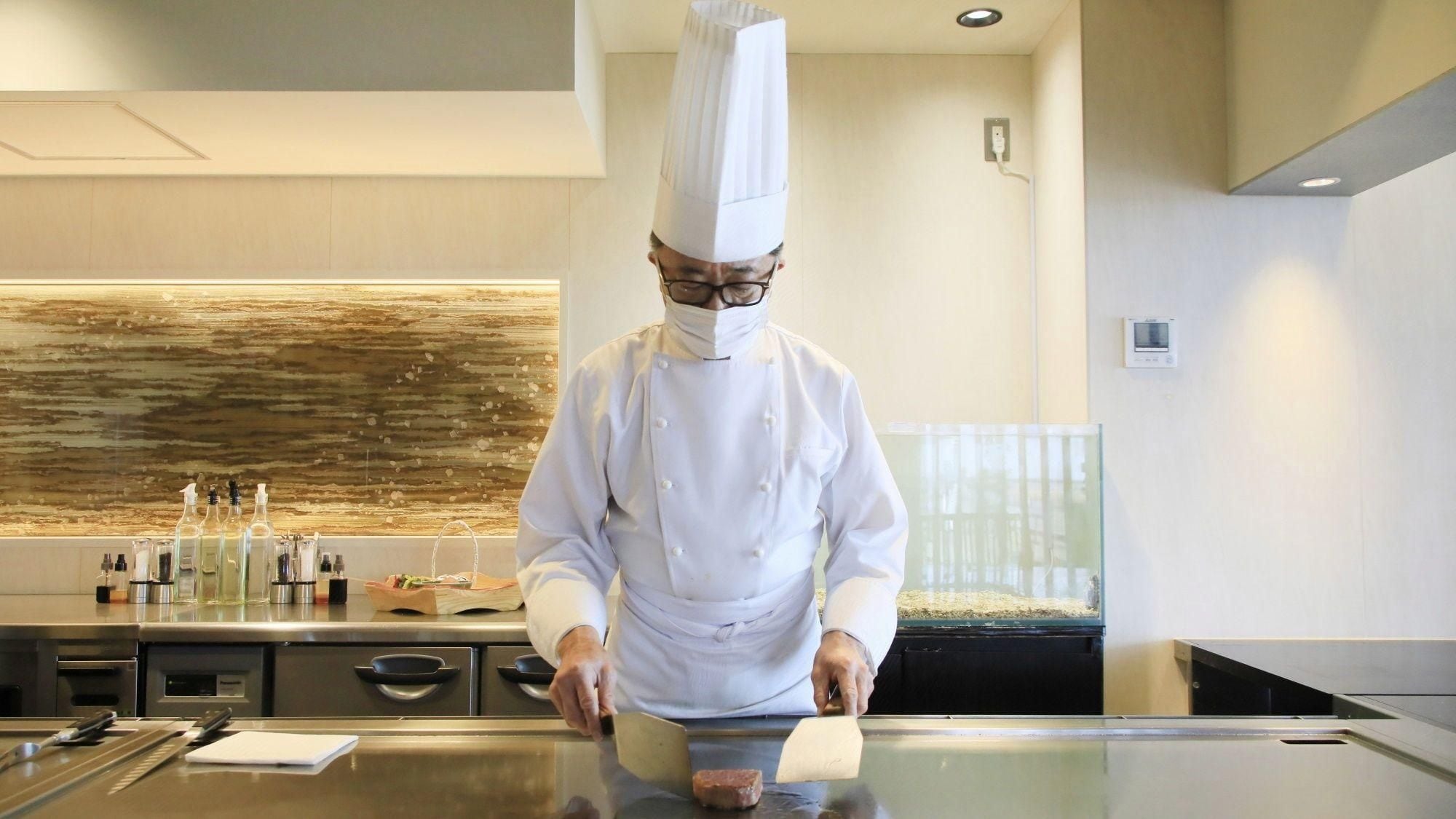 A chef in a professional kitchen with stainless steel appliances and a modern design.