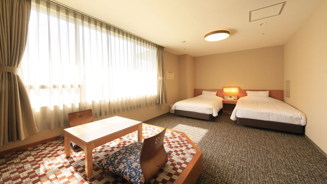 Ett hotellrum med två sängar, ett skrivbord och en stol.
