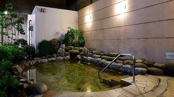 A hot spring area with a stone pool, steps, and a metal railing.