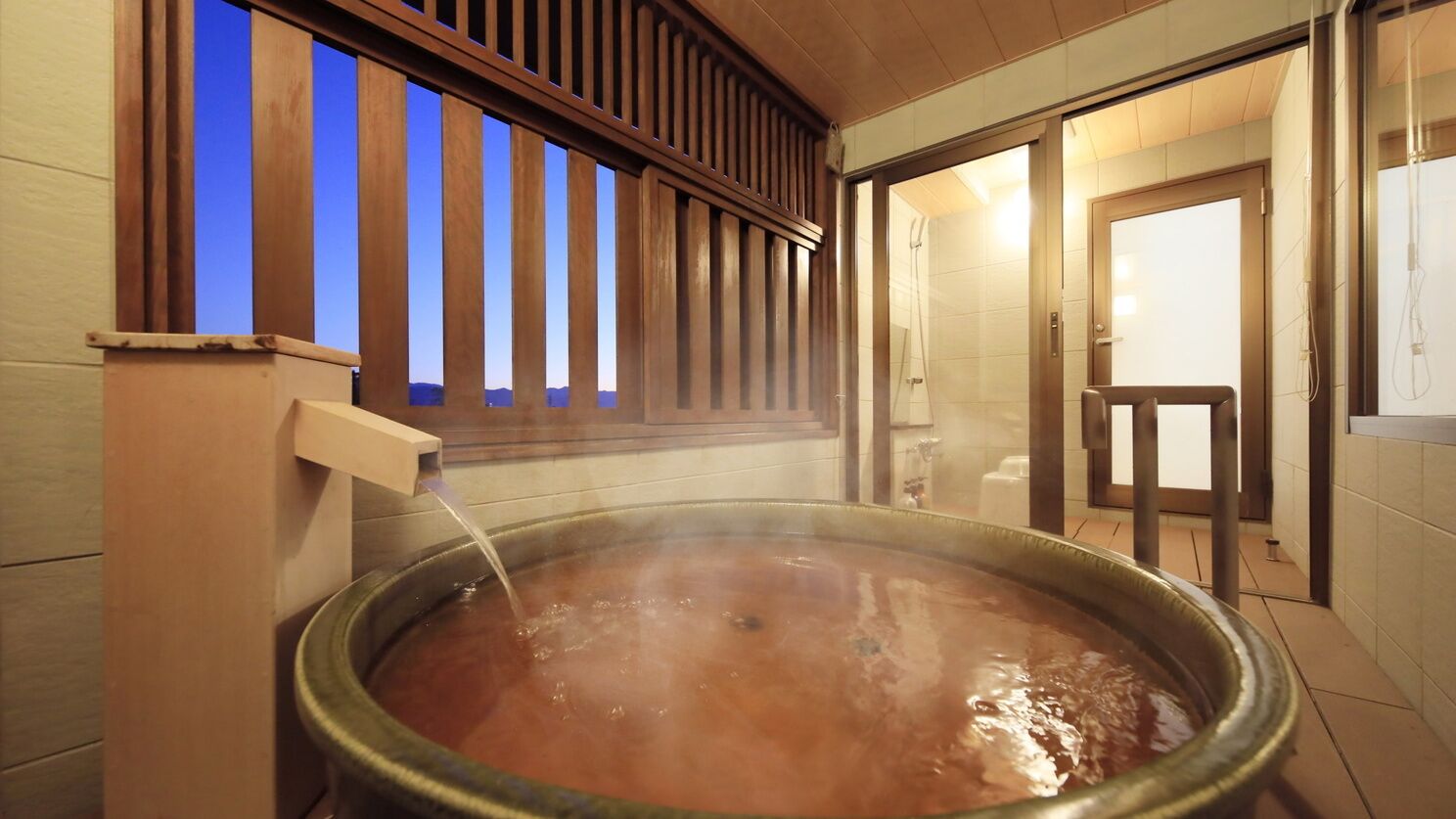 Un baño de aguas termales con barandilla de madera y vista al exterior.