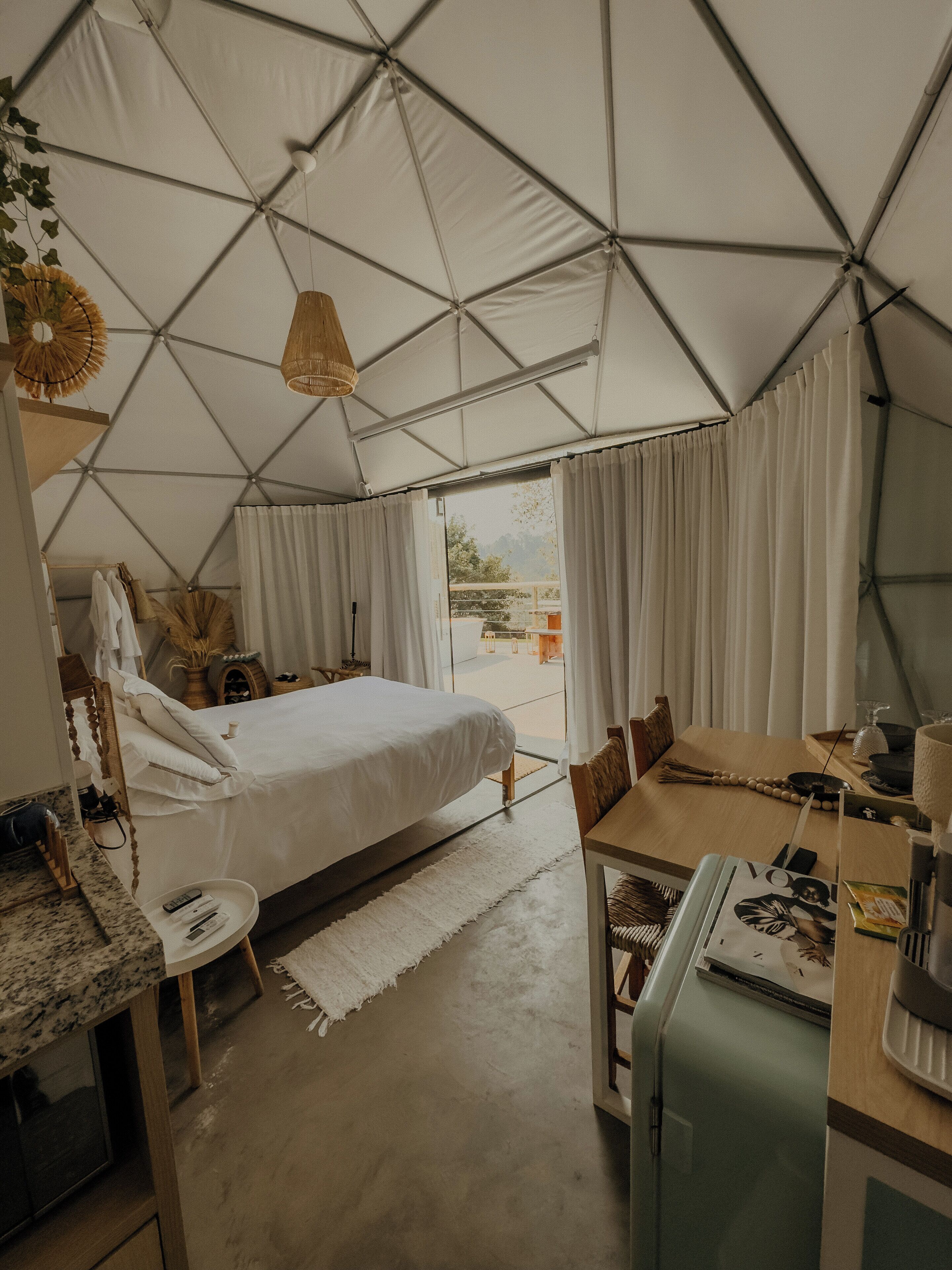 A tented accommodation with a bed, a dining area, and a kitchenette.