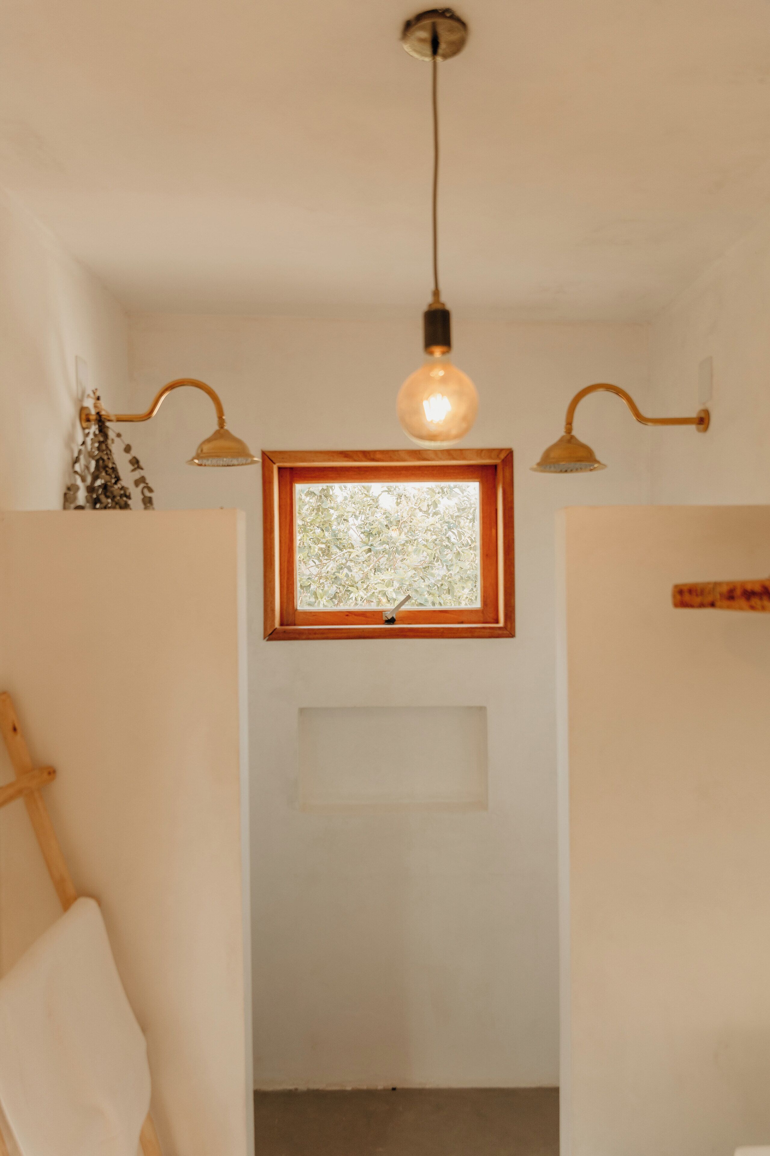 Una habitación con ventanal de madera, una lámpara colgante y una lámpara de pared.