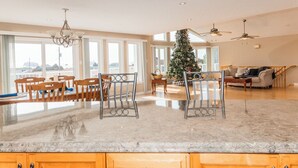 Een ruime keuken met een groot kookeiland, houten stoelen en een kerstboom.