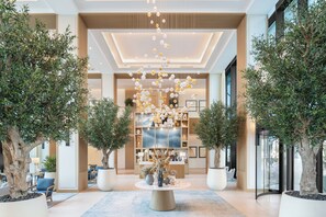 A spacious lobby with a central reception desk, potted trees, and a modern chandelier. - Vida Beach Resort Marassi Al Bahrain (Manama)