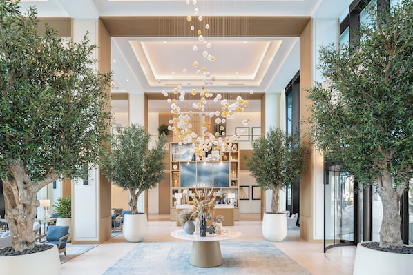A spacious lobby with a central reception desk, potted trees, and a modern chandelier. - Vida Beach Resort Marassi Al Bahrain (Manama)