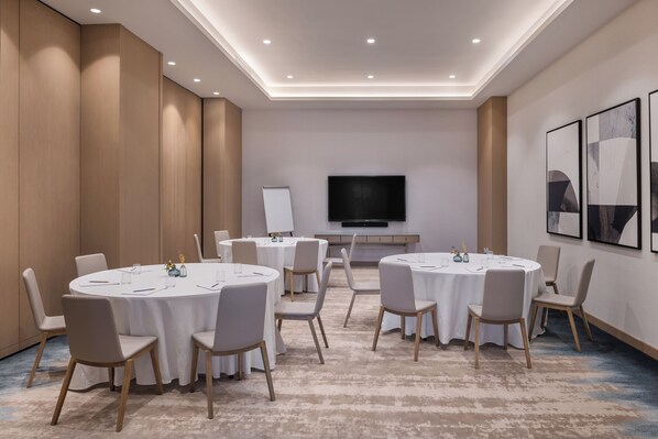 A conference room with round tables, chairs, a whiteboard, and a TV. - Vida Beach Resort Marassi Al Bahrain (Manama)