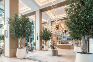 A spacious lobby with large potted trees, a reception desk, and modern lighting fixtures. - Vida Beach Resort Marassi Al Bahrain (Manama)
