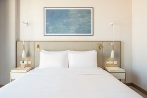 A hotel room with a large bed, two bedside tables with lamps, a wall-mounted artwork, and a plain wall. - Vida Beach Resort Marassi Al Bahrain (Manama)