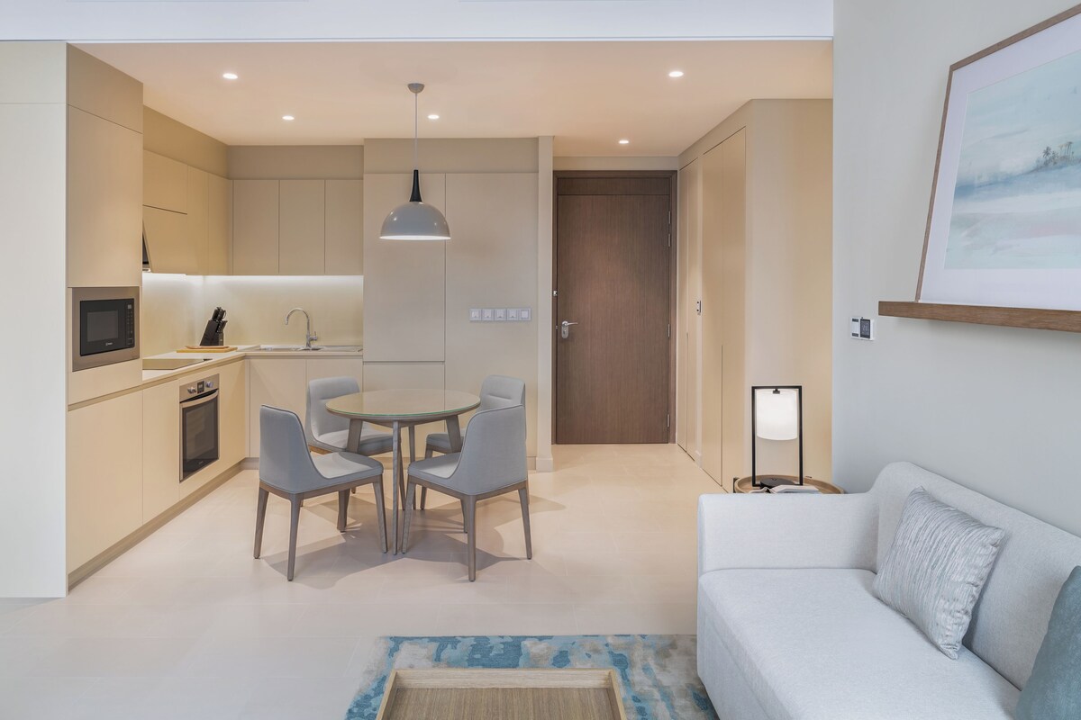 A modern kitchen with a dining area, a white sofa, and a framed picture on the wall.