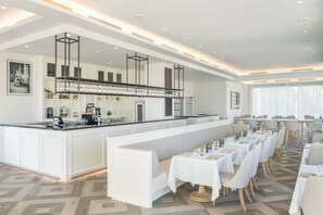 A modern restaurant with a long counter, white booths, and a bar area. - Vida Beach Resort Marassi Al Bahrain (Manama)