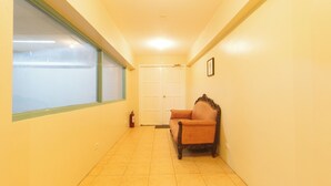 Un pasillo estrecho con una ventana, una puerta y una silla.