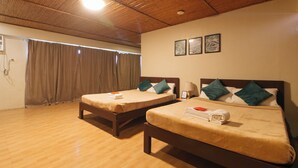 Habitación de hotel con dos camas, suelo de madera y techo con paneles de madera.