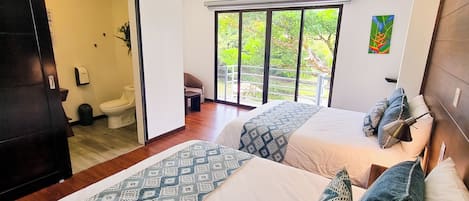 Una habitación de hotel moderna con dos camas, un ventanal con vistas a zonas verdes, un cuadro en la pared y una lámpara en el techo.