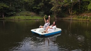A small boat on a calm lake surrounded by lush greenery. - Burbi Lake Lodge (Cabeceras)
