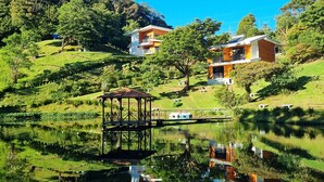 A serene lakeside setting with a gazebo, a small boat, and a building with a solar panel. - Burbi Lake Lodge (Cabeceras)