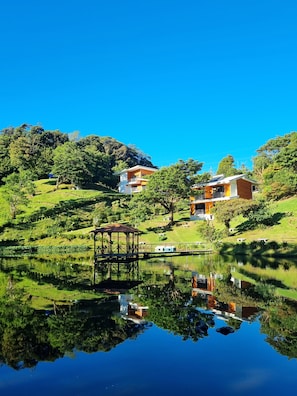 A serene lakeside setting with a gazebo, a small boat, and a building with a solar panel. - Burbi Lake Lodge (Cabeceras)