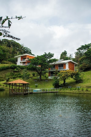A modern house with a balcony, situated by a calm lake, surrounded by lush greenery. - Burbi Lake Lodge (Cabeceras)