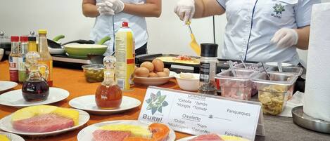 Montaje de bufé con diferentes alimentos y dos empleados sirviendo.