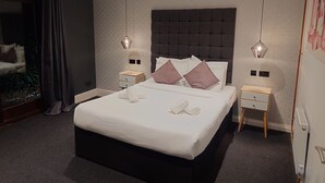 Una habitación de hotel moderna con una cama grande, dos mesitas de noche y vistas a un jardín a través de un ventanal.