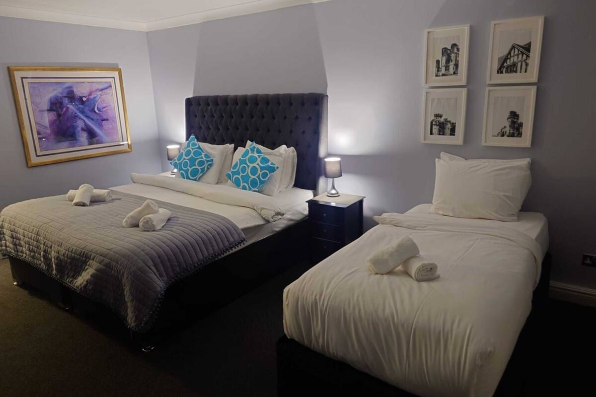 A hotel room with two beds, a dark headboard, and a large abstract painting on the wall.