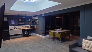 Una cocina moderna con lavadora integrada, un comedor con mesa y sillas, y un sofá.