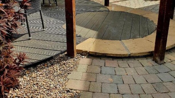Ein Außenbereich mit einer Holzpergola, Tischen und Stühlen.