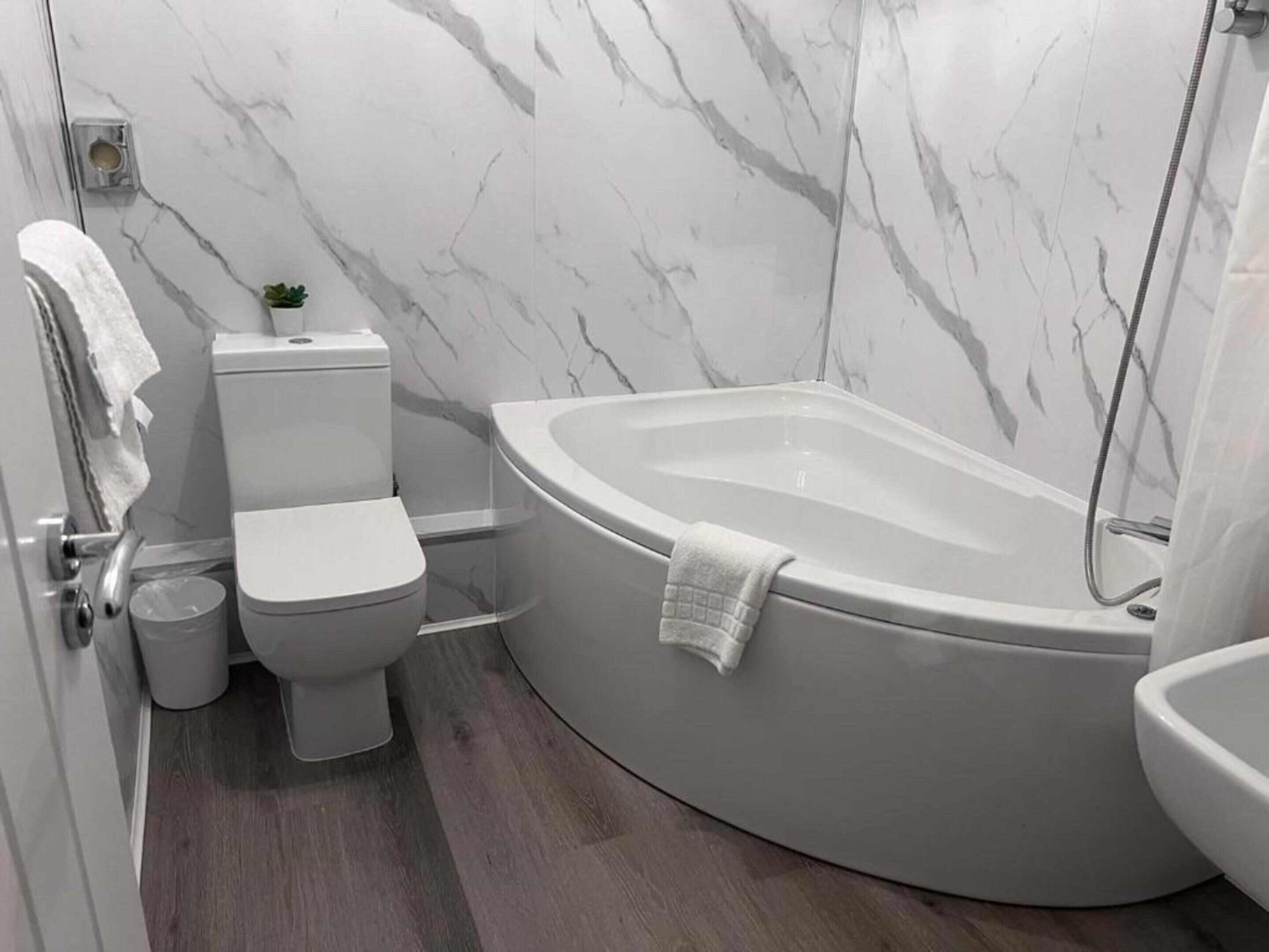A modern bathroom with a toilet, bidet, and a freestanding bathtub.