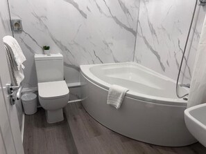 A modern bathroom with a toilet, bidet, and a freestanding bathtub. - Dancenter East Midlands Airport (Derby)
